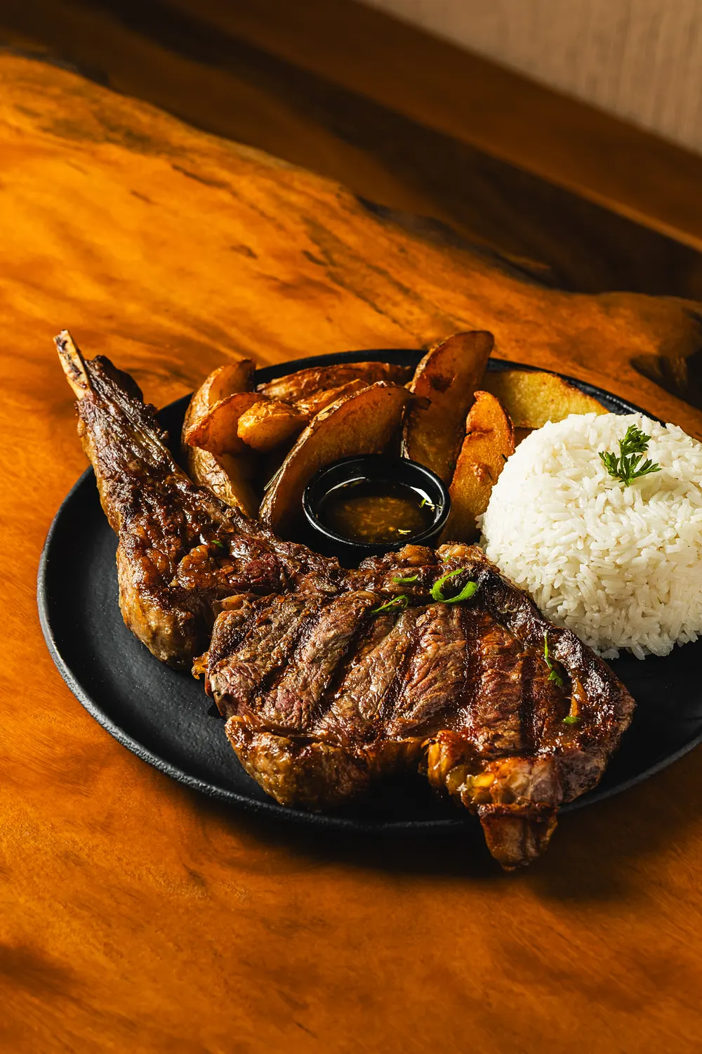 Bisteca grelhada com batatas e arroz sobre mesa de madeira